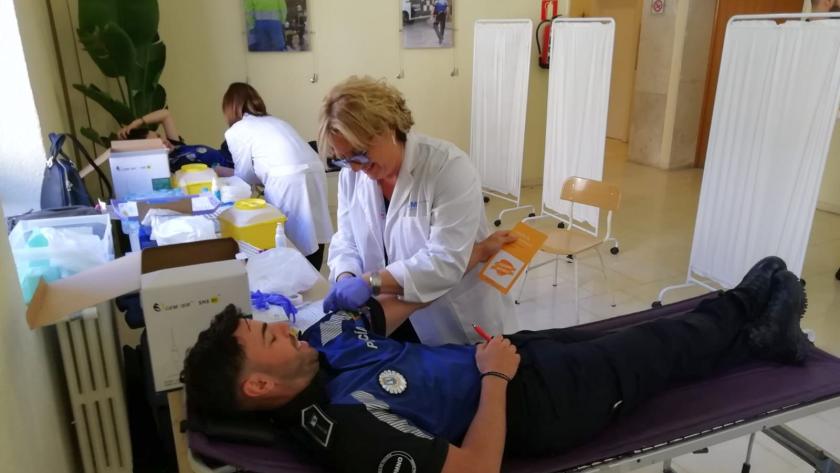 Enfermera extrae muestra de sangre a policía para su registro como donante de médula Enfermera extrayendo tubos de sangre a policía