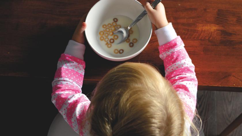 Niña comiendo un bol con leche y cereales