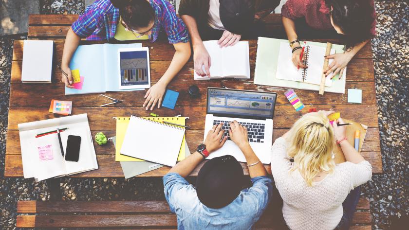 Jóvenes intercambiando ideas en una mesa de trabajo Grupo de jóvenes trabajando en una mesa