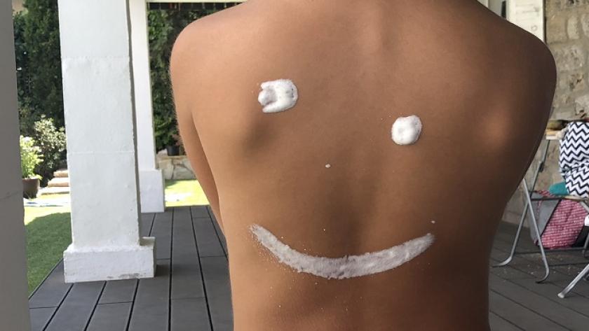 Espalda con crema haciendo el dibujo de una sonrisa