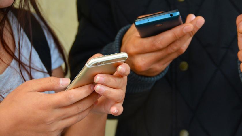 Un hombre y una mujer mirando sus teléfonos móviles