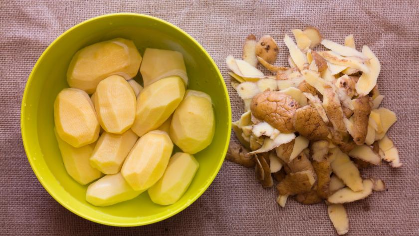 Cuenco con patatas enteras peladas, y piel separada del cuenco