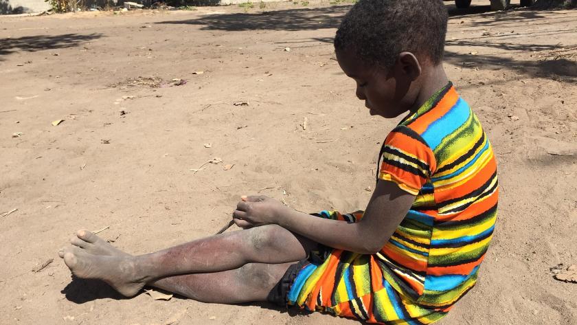 niña africana sentada en suelo de tierra