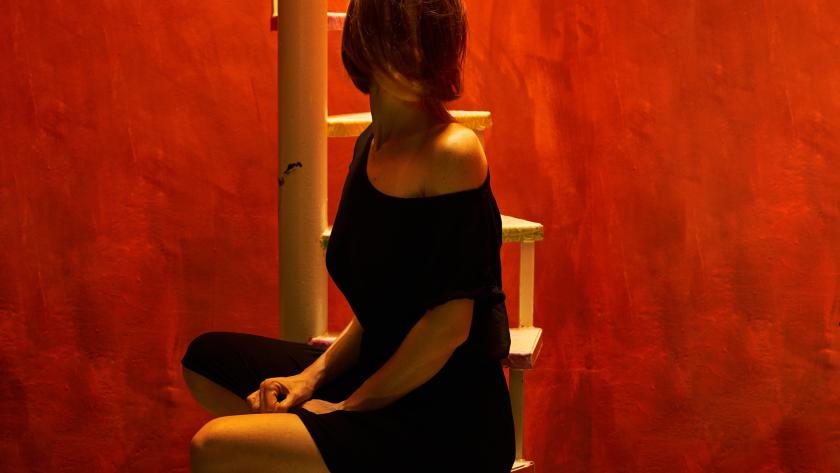 mujer sentada en escalera sobre fondo rojo