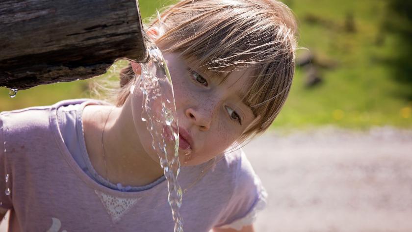 niña bebiendo de una fuente
