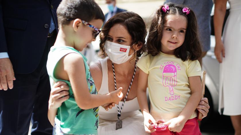 Díaz Ayuso posando agachada con dos niños