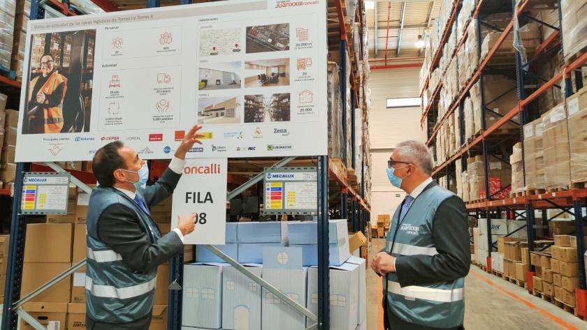 El consejero de Administración Local y Digitalización, Carlos Izquierdo, visita el servicio de digital data de la Fundación Juan XXIII El consejero observa un cartel y escucha a un trabajador que le comenta el proceso de digitalización