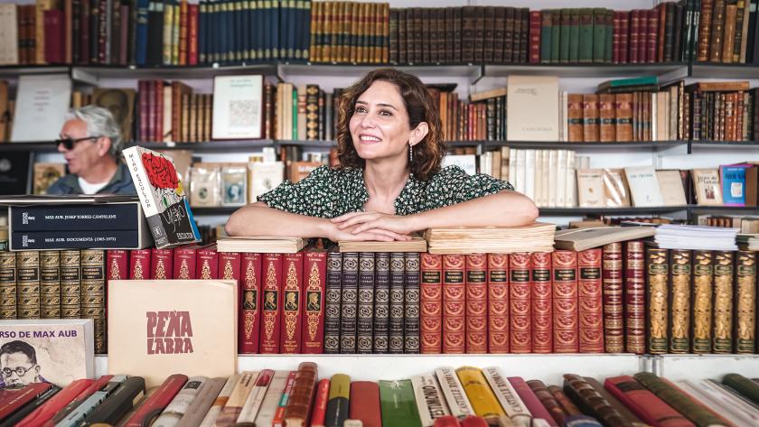 La presidenta sonríe apoyándose de algunos libros en visita la feria