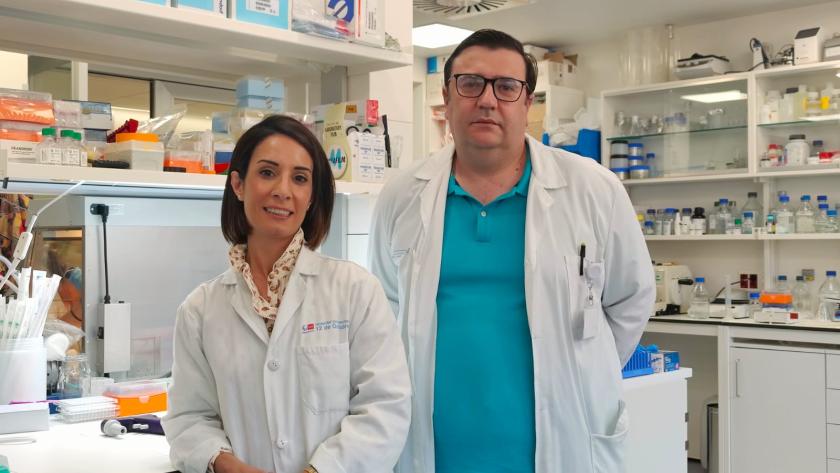 Una médica y un médico, ambos con bata, posando delante del laboratorio
