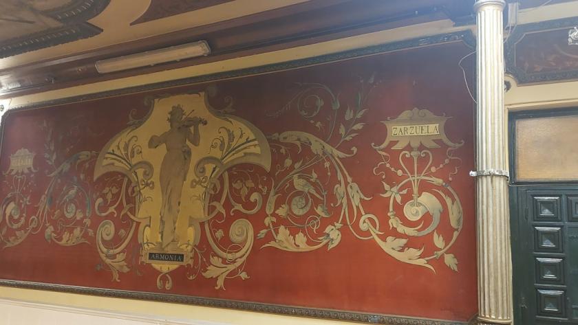 mujer tocando el violín sobre fondo dorado, decoración vegetal e inscripciones con las palabras Armonía, Ópera y Zarzuela