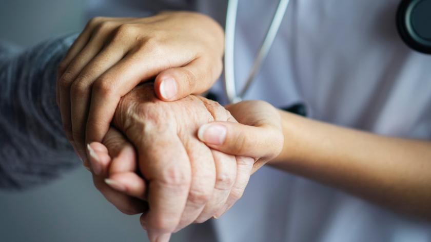 Manos de un sanitario sujetando la mano de una persona mayor
