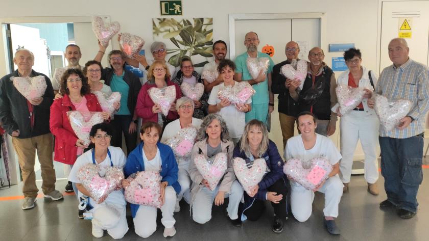 Personas de pie y arrodilladas sostienen cojines con forma de corazón
