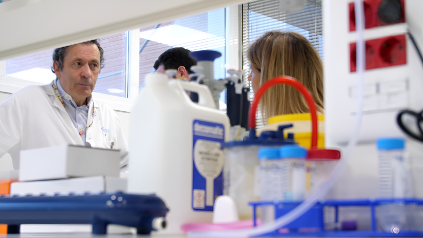 Luis Paz-Ares en su laboratorio con parte de su equipo. Un hombre con bata blanca en un laboratorio al fondo en primer plano material.