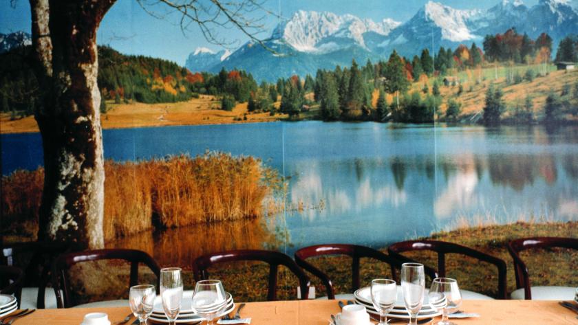 Mesa con vasos y tazas frente aun paisaje de montañas y un lago