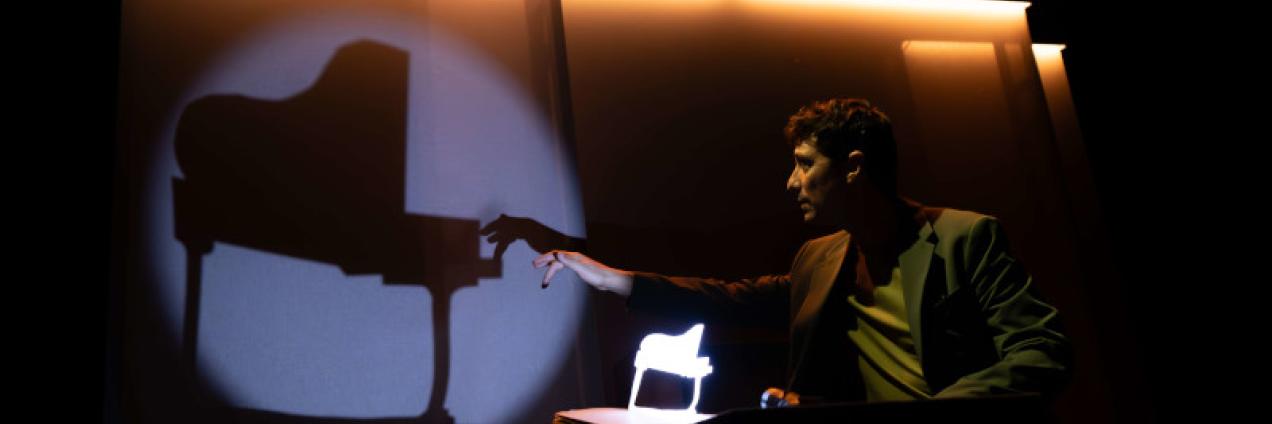 Fotografía del mago tocando el piano en una sombra proyectada sobre una pantalla