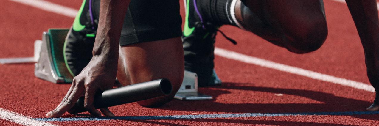 Atleta en posición de salida sujetando testigo de relevos