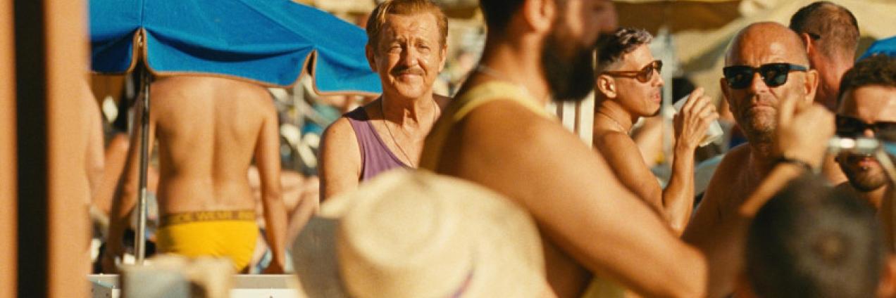 Fotograma que muestra un hombre en una playa abarrotada de personas y sombrillas