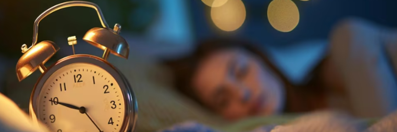 Una mujer duerme con un reloj despertador al lado