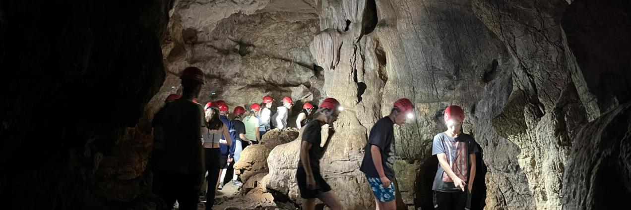 Jóvenes dentro de una cueva con cascos rojos