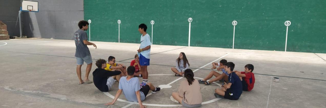 Grupo de jóvenes en círculo en una pista de frontón