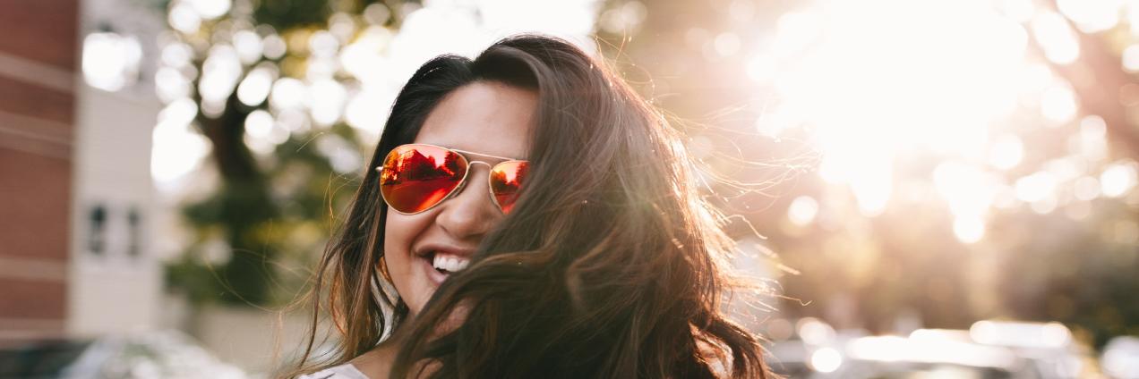 Chica con gafas de sol y pelo suelto sonriendo