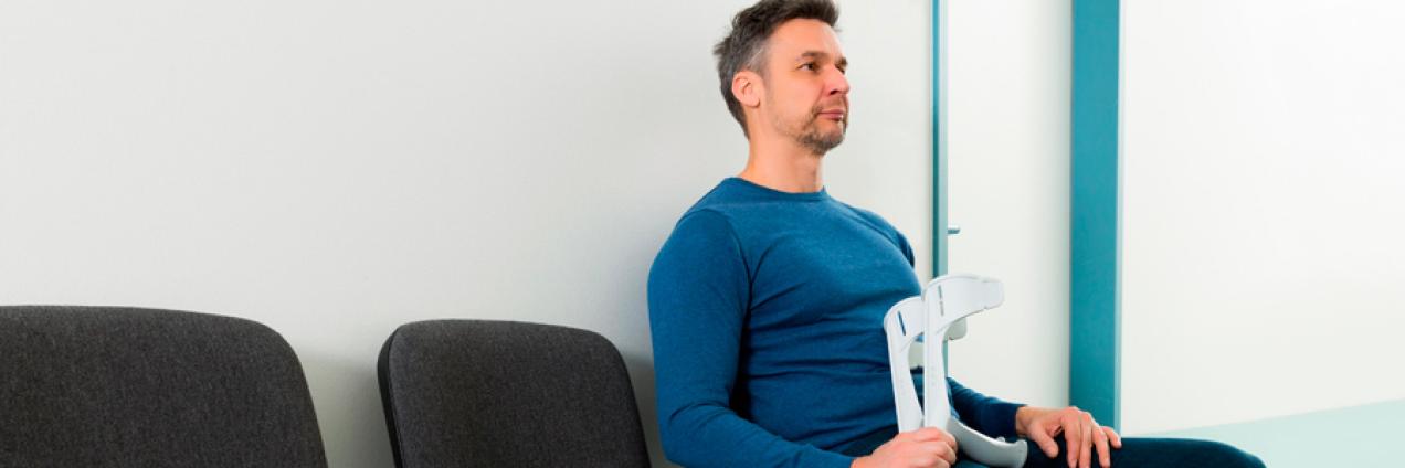 Imagen ilustrativa de un hombre con muletas en una sala de espera