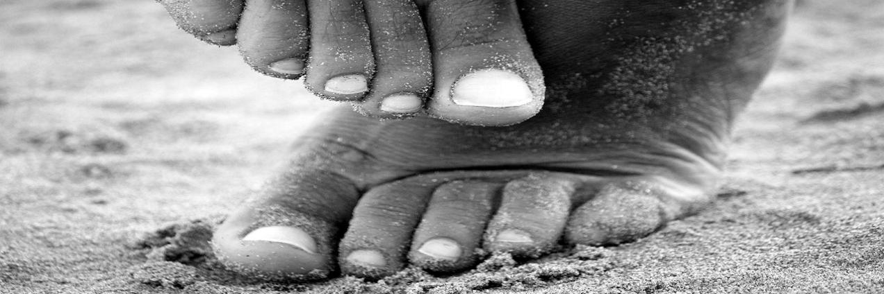 Pies en blanco y negro sobre arena de playa