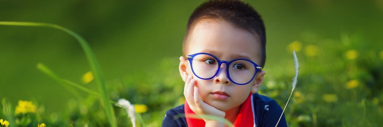 Niño con unas gafas puestas de colora azul, en el campo