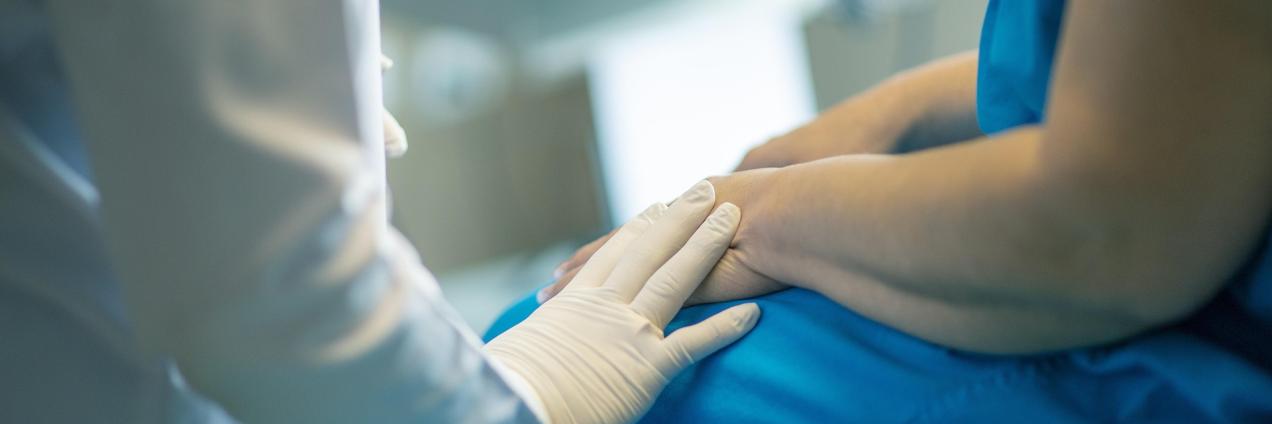 Profesional sanitario consuela con su mano puesta en el brazo del paciente