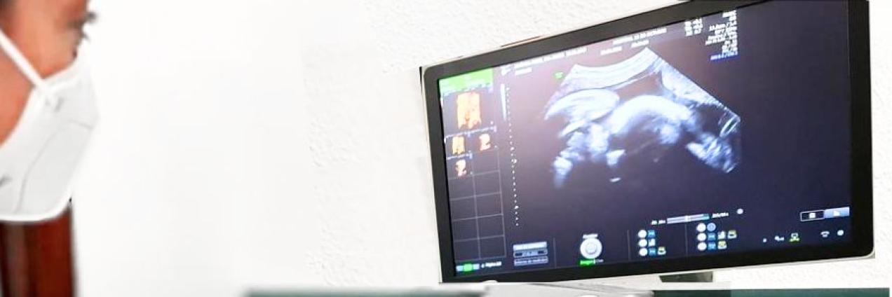 Profesional con bata blanca a la izquierda y niña a la derecha y juntas sostienen un modelo 3D de corazón