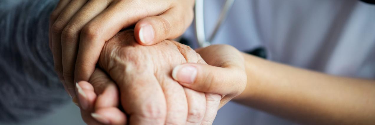 Un sanitario coge las manos de una persona mayor