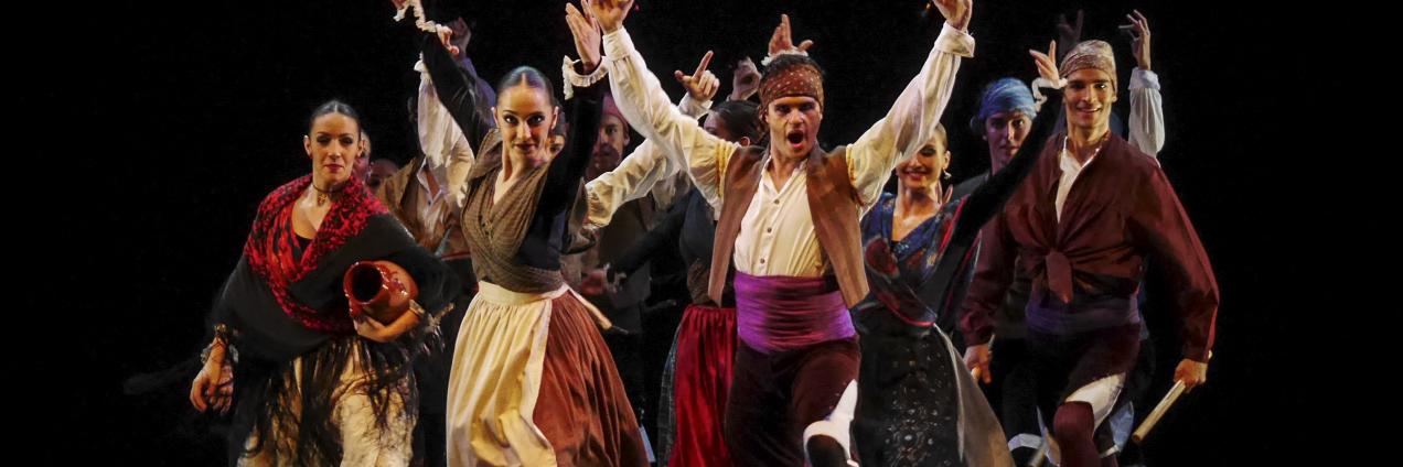 Grupo de bailarines en un escenario levantando las manos