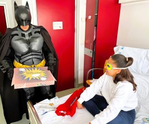 Un súper héroe caracterizado visita a una paciente en un hospital