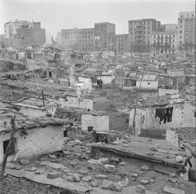 Chabolas de Jaime el Conquistador, 1957. Juan Pando Barrero. Fototeca IPCE imagen de un descampado con chabolas y edificios al fondo