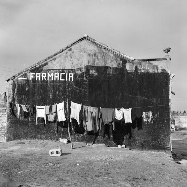 Madrid inédito. Chabolas en la Plaza de Castilla, 1964. Juan Miguel Pando Barrero. Fototeca IPCE Imagen de una fachada con ropa tendida y el letrero Farmacia