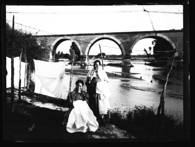 Dos lavanderas posando en el río Manzanares con el Puente de los Franceses al fondo