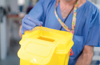 Sanitario depositando aguja en contenedor amarillo
