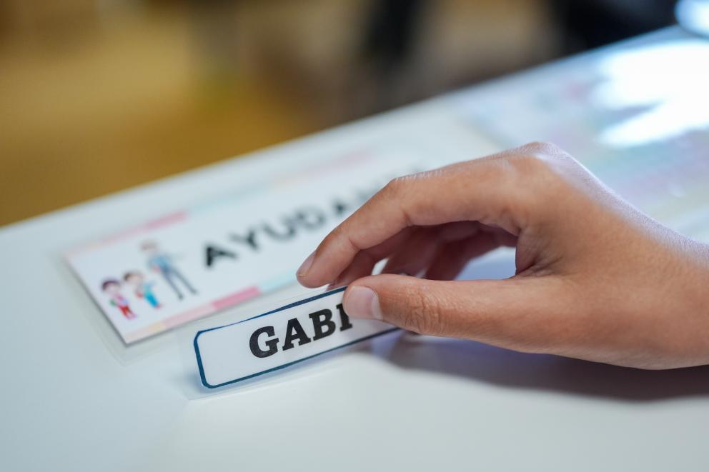Mano sosteniendo una etiqueta con el nombre de un alumno