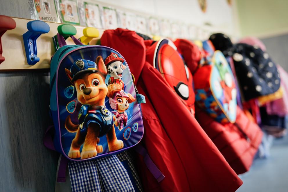 Detalle de percha en colegio con mochilas y abrigos colgados