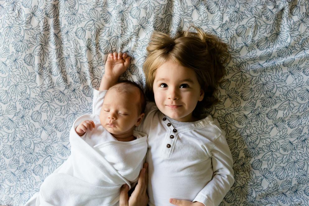 Bebé con su hermana encima de una cama
