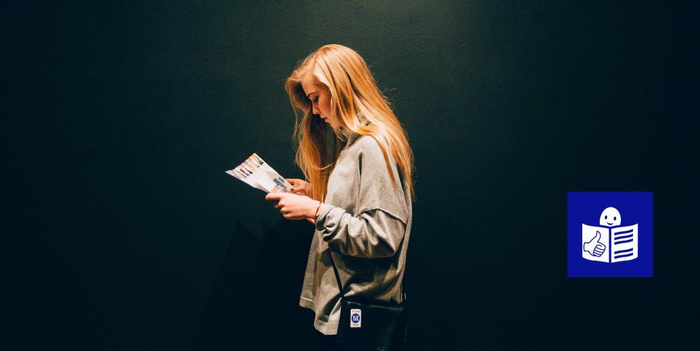 Mujer joven de perfil leyendo un folleto 