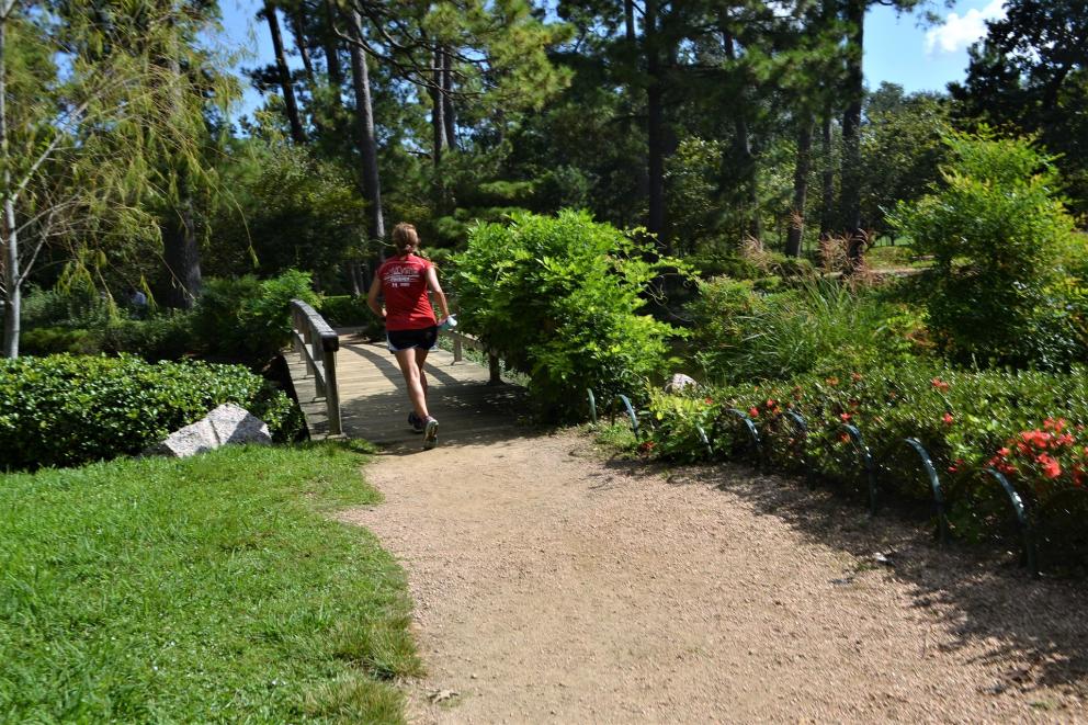 chica cruzando puente en un parque