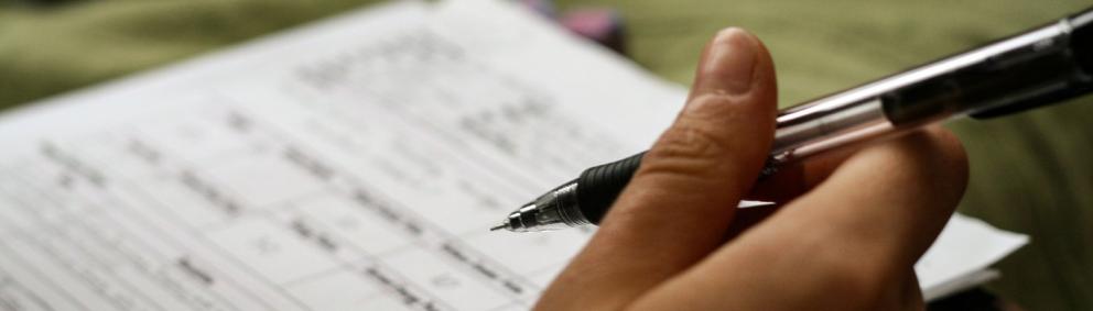 Formulario con una mano sosteniendo una pluma estilográfica