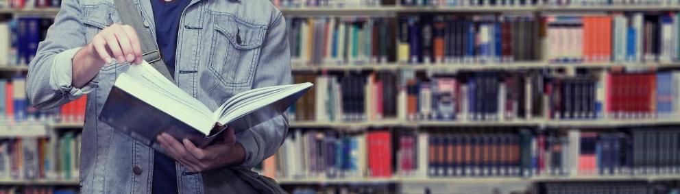 Persona en una biblioteca sosteniendo un libro