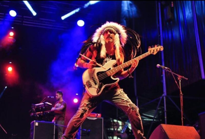 imagen Pepe Bao tocando el bajo en un concierto, lleva un tocado de plumas indio 