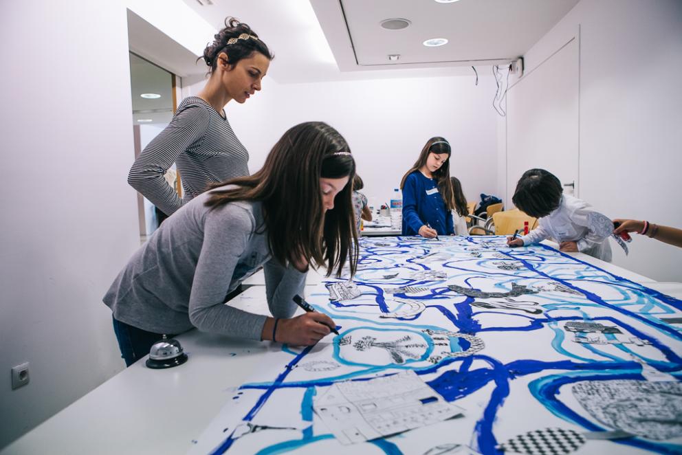 Niños pintando con pinceles líneas curvas en distintos tonos de azul