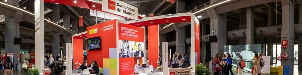 Foto de un expositor de feria con mesas y personas atendiendo al público