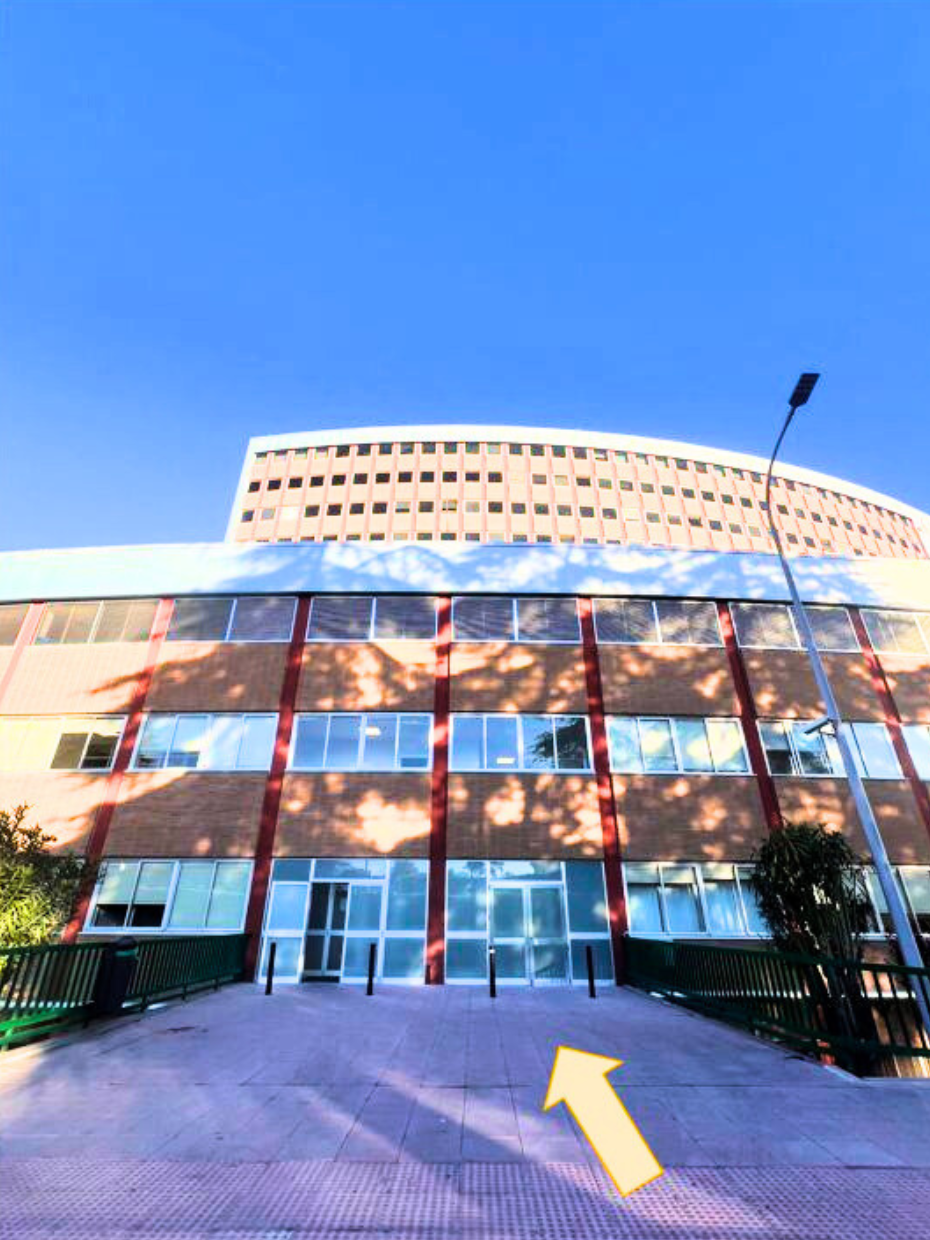 Edificio con flecha que indica entrada por puertas acristaladas