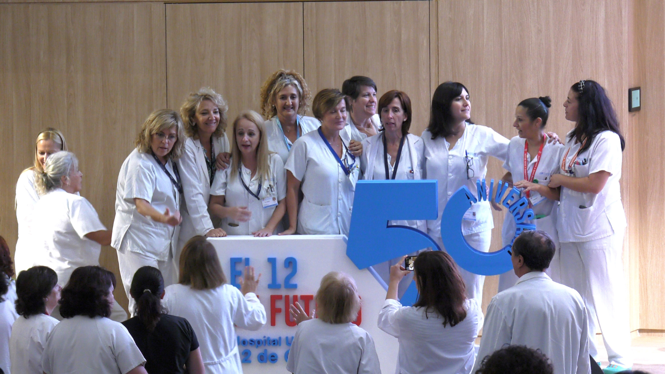 mujeres vestidas con pijama blanco de enfermería apoyadas en un corpóreo que pone el 12 en futuro sobre un escenario