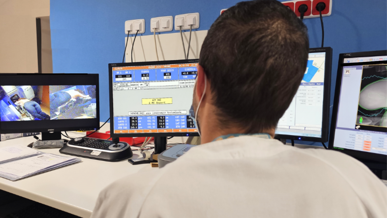 Técnico de espaldas frente a varias pantallas con imágenes de tratamiento rediología